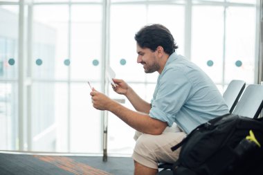 Sırt çantalı adam havaalanında oturuyor.. 