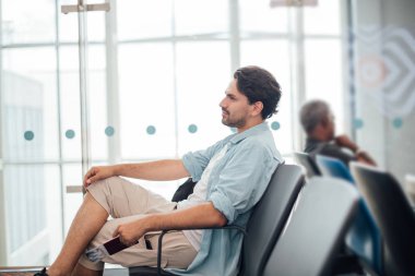 Sırt çantalı adam havaalanında oturuyor.. 