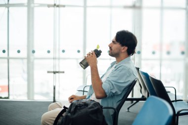 Havaalanında kalkış bekleyen adam, içme suyu. 