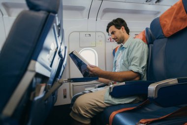 Adam elinde bir dergi yle uçakta uçuyor.