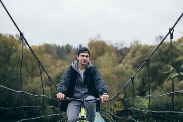 Um homem de bicicleta no outono na ponte . — Fotografia de Stock