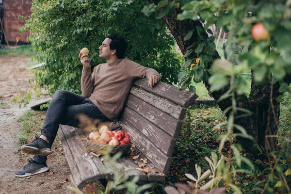 Een mannelijke boer zit op een bankje in de tuin — Stockfoto