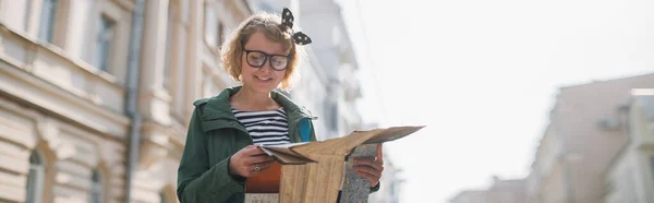 欧洲城市的女游客带着地图 一个手里拿着旅游地图的年轻女子走在欧洲的街道上 在纸质地图上找到旅行路线 — 图库照片