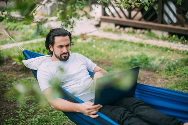 Een Man Werkt Met Een Laptop Een Hangmat Een Landhuis — Stockfoto