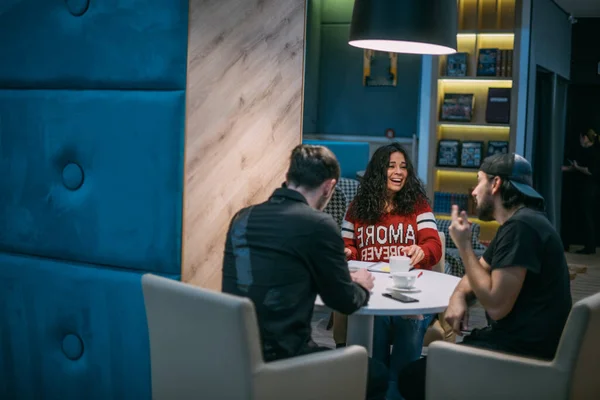 男人和女人在一起工作 年轻人和一个女孩在一个现代化的工作室里讨论工作问题 一队同事坐在一个时髦的房间里的桌子旁进行交流 — 图库照片