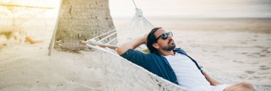 Bir adam sükunetten hoşlanır, okyanusun arka planında bir hamakta yatar ve günbatımını seyreder. Yakışıklı adam tropik bir adanın sahilinde gün batımıyla karşılaşır..