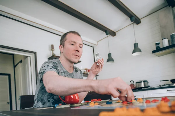 Friends play a board game in the living room. The company of young guys sits at a table and emotionally and cheerfully plays a card game on the weekend