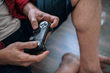 Bir joystick ile erkek ellerine yakın çekim. Yerde otururken video oyunu oynayan adam