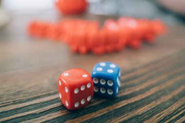 Masa oyunu ve zar yakın plan. Tahta bir masada oyun küpleri ve renkli, canlı bir oyun tahtasının arka planında