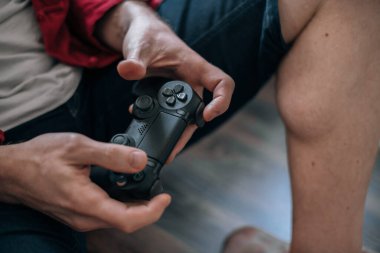 Bir joystick ile erkek ellerine yakın çekim. Yerde otururken video oyunu oynayan adam
