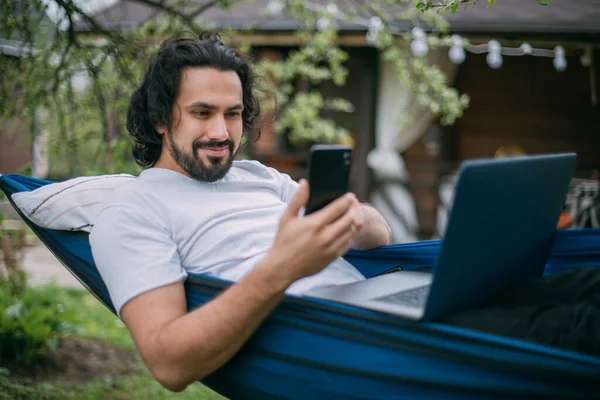 Een Man Werkt Met Een Laptop Een Telefoon Een Hangmat — Stockfoto