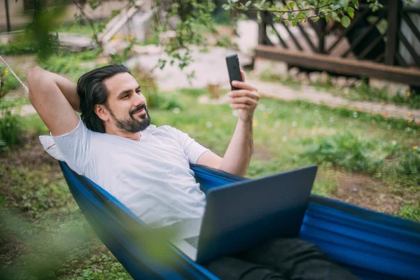 Ein Mann Arbeitet Mit Laptop Und Telefon Einer Hängematte Einem — Stockfoto