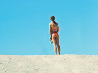 Tepenin tepesinde kırmızı mayosu olan genç bir kız.