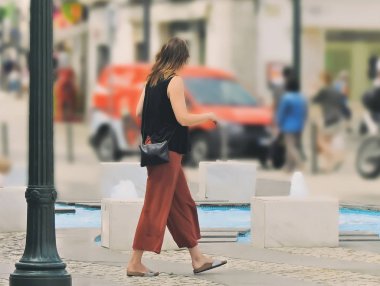 Şehir üzerinden siyah bluz ve sandalet ile genç sarışın