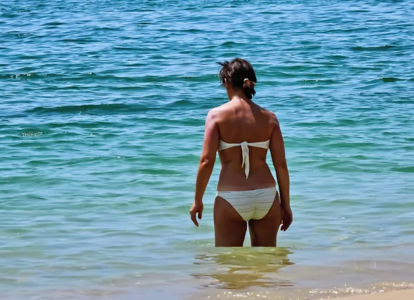 Beyaz mayogiyen kadın suda duruyor