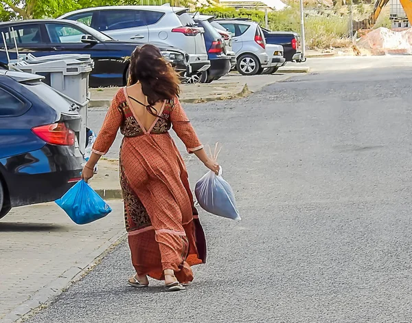 Woman in long dress with garbage bags on a city street