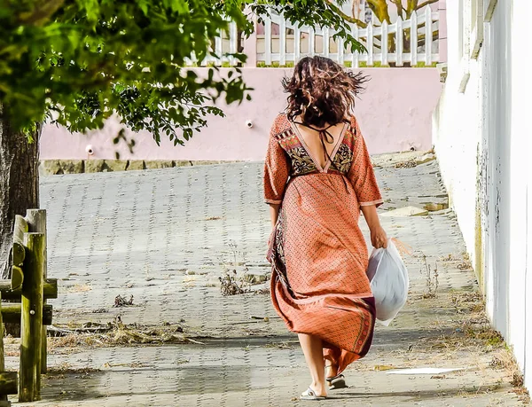 Woman in long dress with garbage bags on a city street
