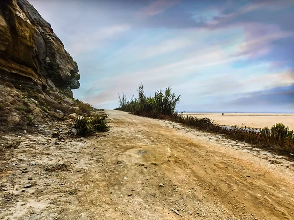 Image from a country road leading to the sea with a cloudy sky