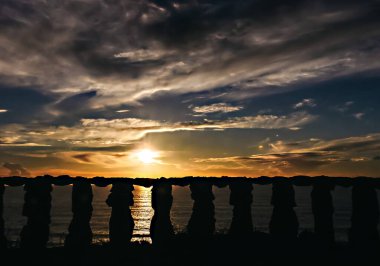 Güneş batarken Portekiz 'in Atlantik Okyanusu kıyısındaki bir kayanın arkasında görüldü.