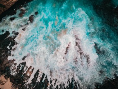 Birds eye view of the broken beach in Nusa Penida, Indonesia. Waves and foam, abstract background, drone photography clipart