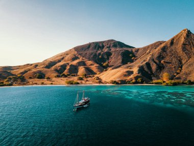 Endonezya 'nın görülebilir resifi olan Komodo Adası' nın önündeki bir dalış teknesinin Kuş Gözü Manzarası. Canlı İHA Vuruşu.