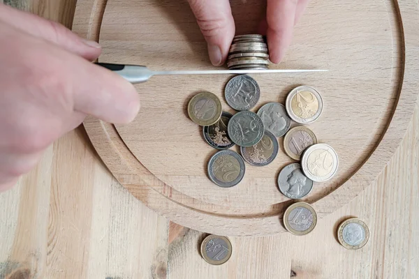 Hände schneiden Euro- und Dollarmünzen mit einem Messer und trennen sie wie Nahrungsmittel. Konzept von Steuern, Betrug oder Gewinn. Ansicht von oben. — Stockfoto