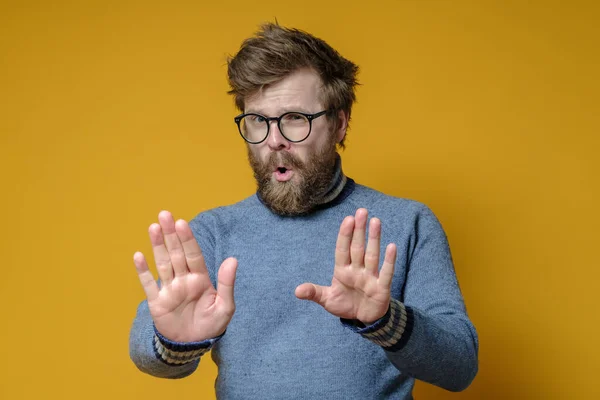 Un hombre tranquilo y seguro hace un gesto de alto con las manos. Shaggy hipster en un viejo suéter hace una señal calmante con palmas . — Foto de Stock