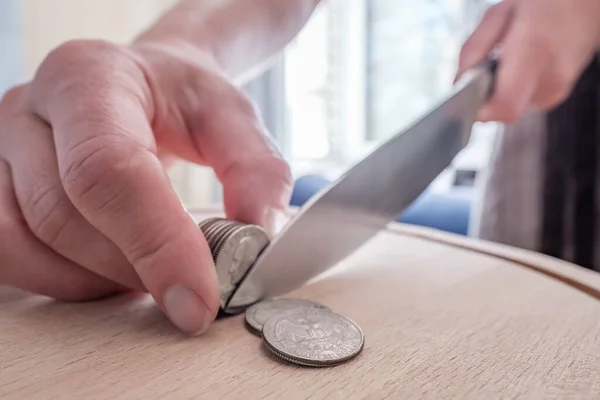 Hände schneiden Dollarmünzen mit einem Messer und trennen sie wie Essensstücke auf einem Schneidebrett. Konzept von Steuern, Betrug oder Gewinn. — Stockfoto