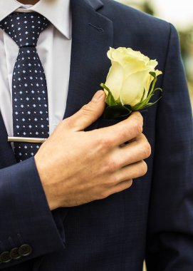Damat yaka çiçeği elini ceketinin cebine koyar.