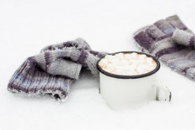 Eski metal bir fincan sıcak kakao ve yanında marshmallowlar duruyordu. Çizgili bir örgü eldivenleri örmüştü.