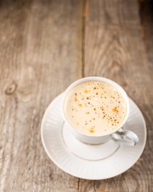 Eski ahşap masada köpüklü nefis bir fincan kahve.