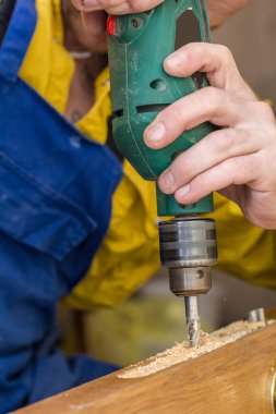 Marangoz eski ahşap kapıda matkap kullanarak mors kilidi açıyor. Yakın plan..