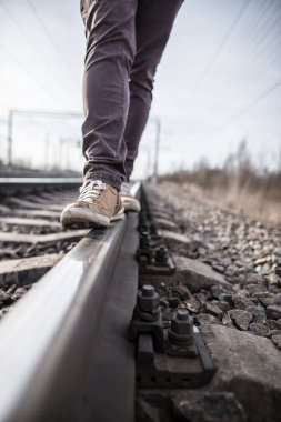 Hippi adam demiryolu boyunca güvenli bir şekilde yürür. Yakın plan..