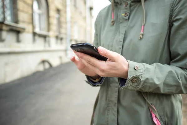 Ein Mädchen Einer Jacke Hält Ein Smartphone Der Hand Während — Stockfoto