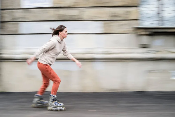 在城市街道上带着运动模糊的年轻女子滑旱冰很可爱 — 图库照片