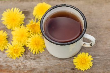 Sarı karahindiba çiçeklerinden (taraxacum officinale) yapılan çay, sıcak bir bahar günü, eski bir fincanda..