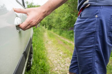 Adam, orman yolunda duran eli ile arabanın kapısını açar, o kapıyı açar. Yakın plan..