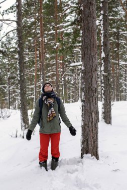 Gülümseyen güzel bir kadın ellerini yana doğru uzatıyor ve kışın karla kaplı ormanına hayran kalıyor. Doğanın korunması kavramı.