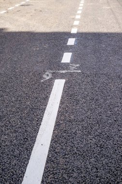 Beyaz katı çizgiler yeni asfalt yolda aralıklı hale geliyor. Yakın plan..
