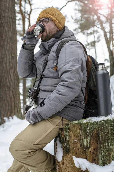 Yakışıklı Gözlüklü Kameralı Sırt Çantalı Bir Adam Kış Ormanındaki Ağaç — Stok fotoğraf