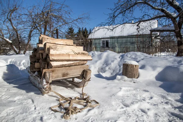 庭と家 美しい霜の晴れた日の背景を背景に 雪に覆われた道に薪が立つヴィンテージの木製のそり — ストック写真