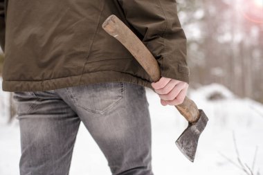 Elinde balta olan bir adam kışın karla kaplı ormana gider, dondurucu bir günde. Yakın plan..