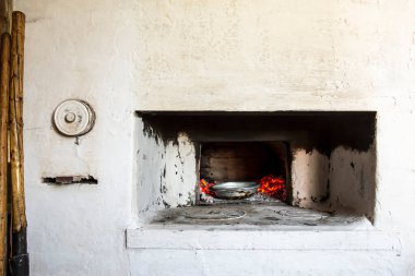 Eski, geleneksel Rus köy ocağı. Sıcak fırından kömürlü tabakları almak için gerekli aletler (maşalar, kürek) yakınlardadır.