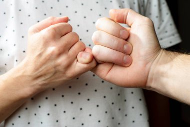 İki kavgacı adam ve kadın barıştılar ve küçük parmaklarıyla parmak hareketi yaparak yemin ettiler.