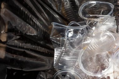 Birçok plastik bardak kullanılıyor, buruşturuluyor ve parti sonrasında siyah çöp torbasıyla kaplı bir çöp kutusuna konuyor. Çevresel sorun kavramı.