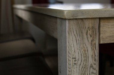 Masanın köşesine bak. Ahşap bir dokusu ve pürüzsüz tezgahı var. Pencereden doğal ışık saçıyor. Yakın plan..