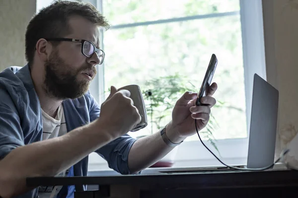 Ein Nachdenklicher Bärtiger Mann Mit Brille Hält Ein Smartphone Und — Stockfoto