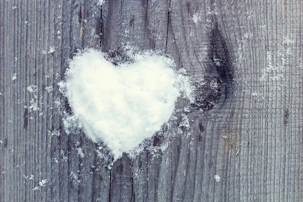 Heart of snow on a wooden fence, overcast winter day.