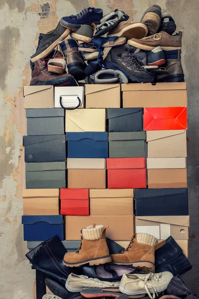 みすぼらしい壁の背景に折り畳まれた段ボール箱と靴の多くの様々なスタック — ストック写真