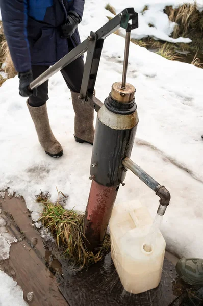 Ein Mann Gießt Einem Winterabend Dorf Wasser Mit Einer Wasserpumpe — Stockfoto